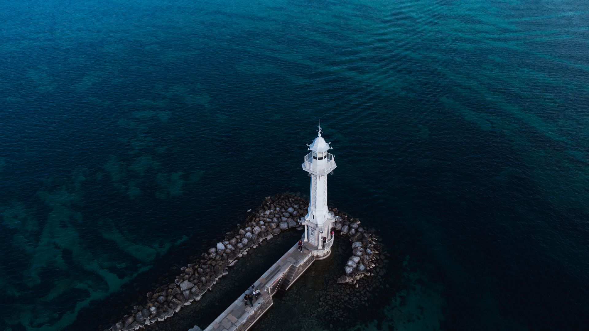 White lighthouse by the sea, aerial view