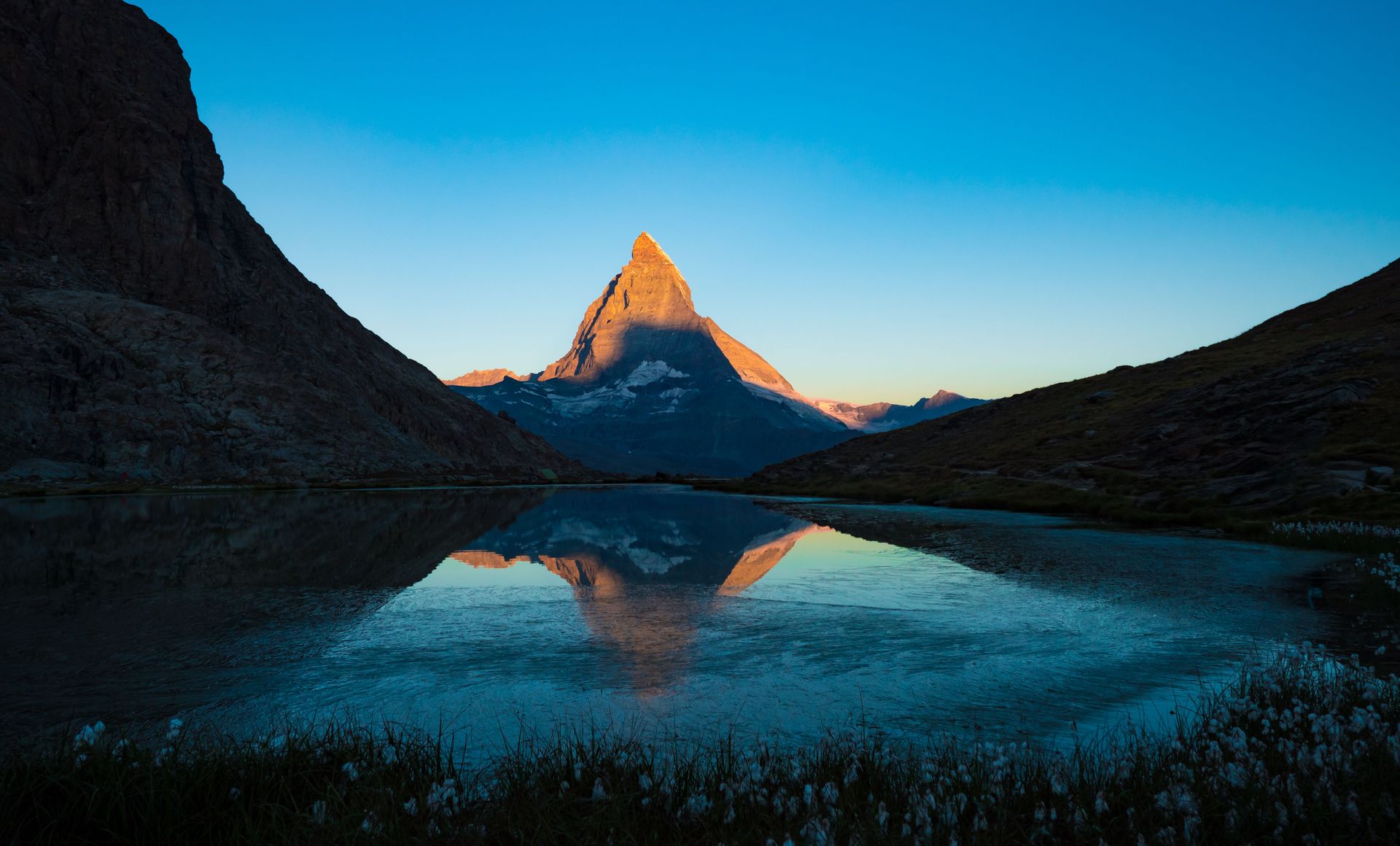 Sonnenbeschienener Berggipfel, der sich in einem Bergsee spiegelt